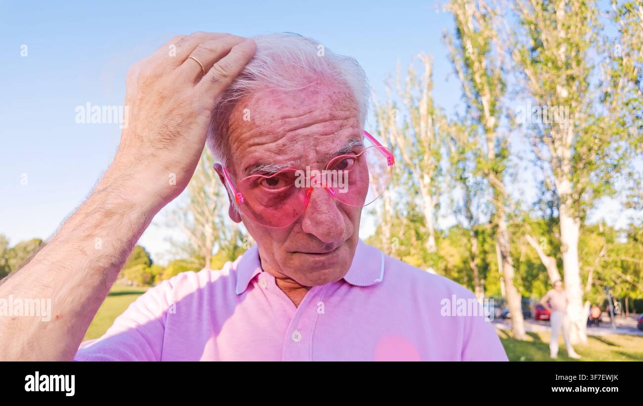 Homme âgé portant des lunettes de soleil en forme de cœur dans un parc Banque D'Images
