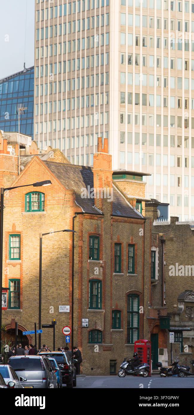 Usagers et circulation dans Wilfred Street, Londres. Une cabine téléphonique rouge se dresse devant des bâtiments historiques en briques et les tours de bureaux modernes de Victoria. Banque D'Images