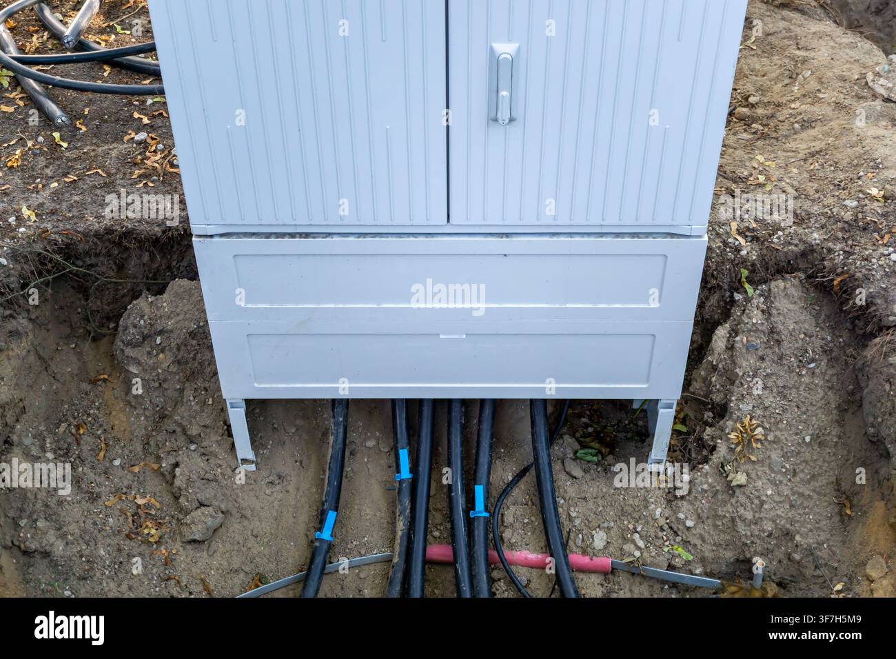 Câbles d'alimentation souterrains entrant dans un tableau de distribution électrique lors de travaux de construction dans un quartier résidentiel en Allemagne. Banque D'Images