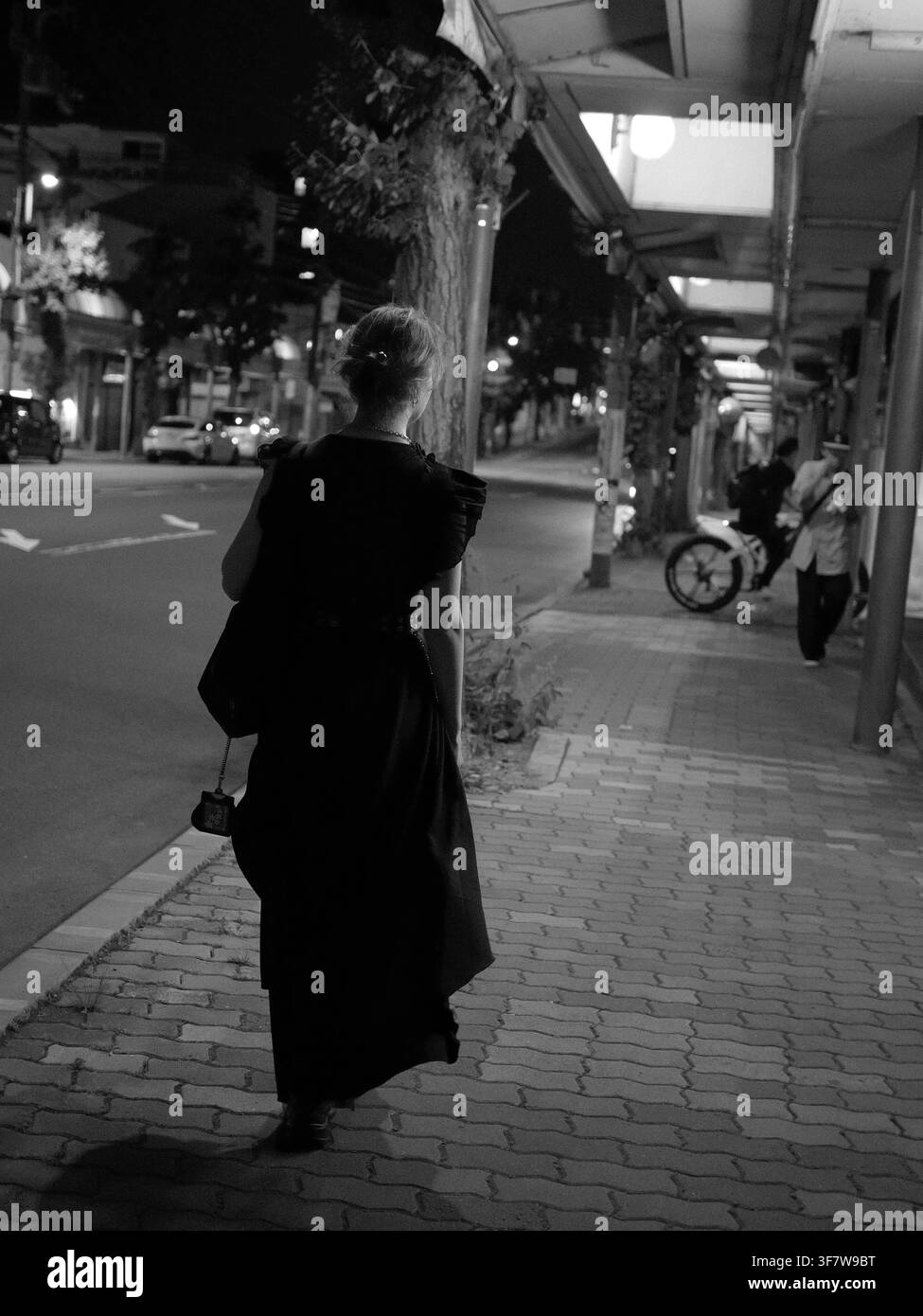 Femme en robe sombre marchant sur un trottoir la nuit à Higashiyama, Kyoto, Japon Banque D'Images