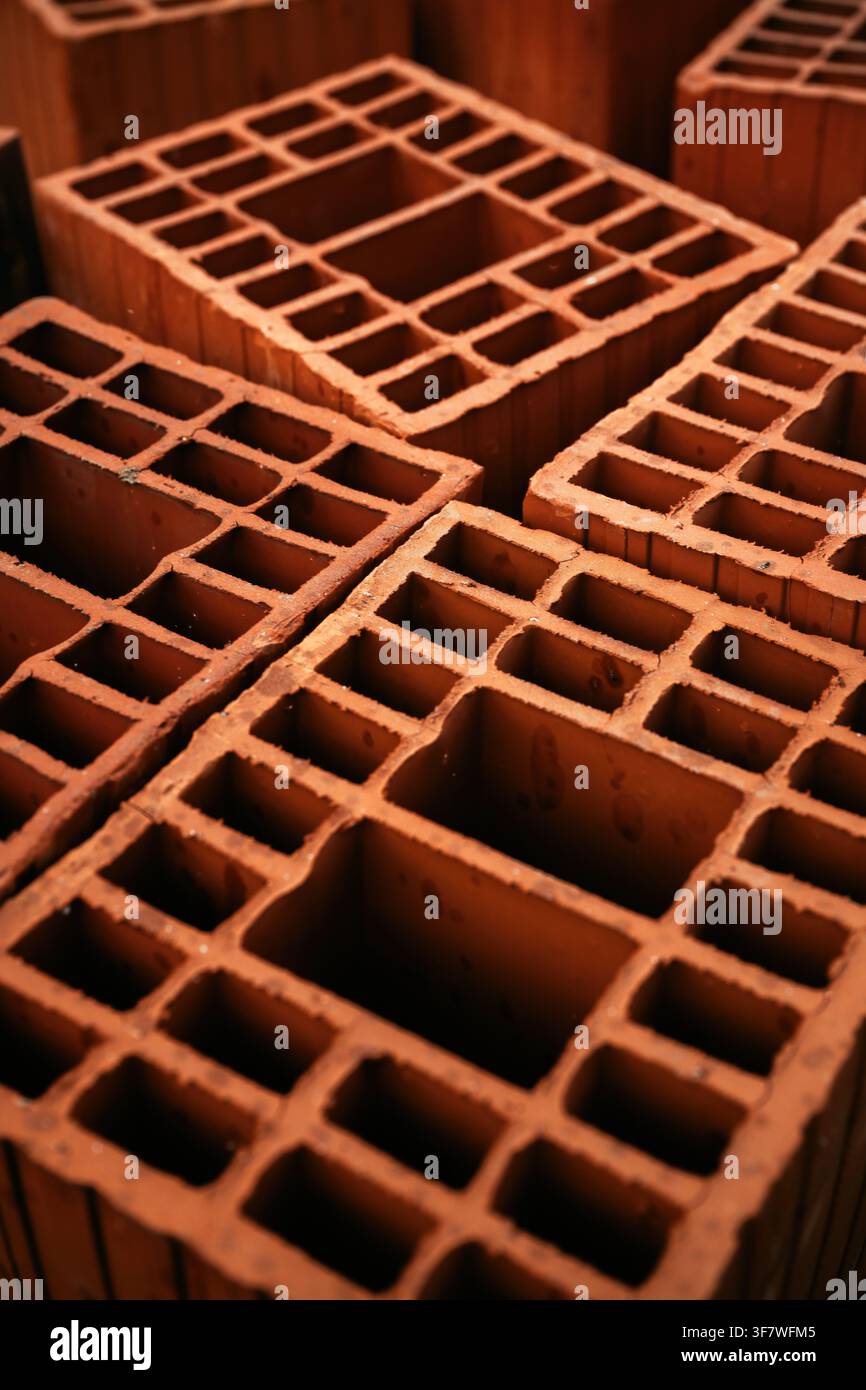 Gros plan en hauteur de blocs de briques creuses empilés en terre cuite, montrant leurs structures géométriques internes en nid d'abeille. Mise au point sélective. Banque D'Images