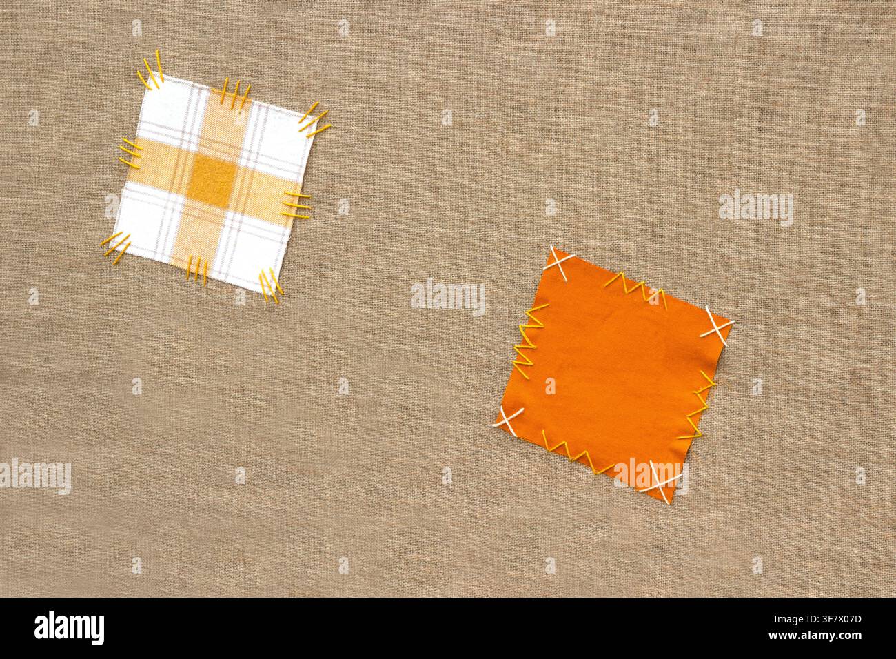 Deux écussons sont cousus sur du tissu de sac avec une couture à la main grossière. Banque D'Images