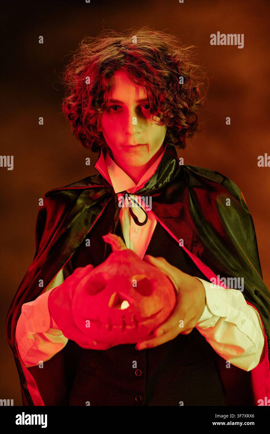 Portrait d'un adolescent en costume de vampire tenant une citrouille d'Halloween Banque D'Images