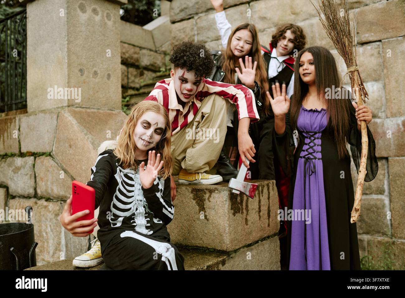 Divers adolescents en costumes d'Halloween prenant un selfie sur un smartphone Banque D'Images