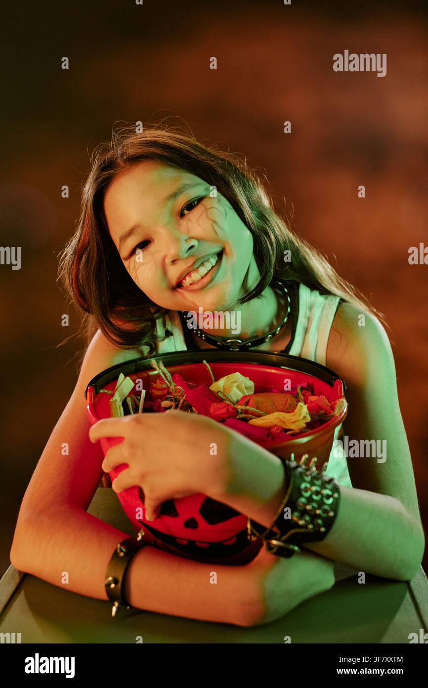Portrait d'une jeune Asiatique souriante avec un seau de bonbons d'Halloween Banque D'Images
