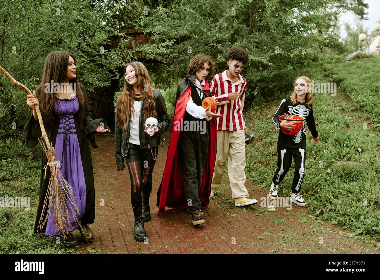 Divers adolescents en costumes d'Halloween marchant et célébrant à l'extérieur Banque D'Images