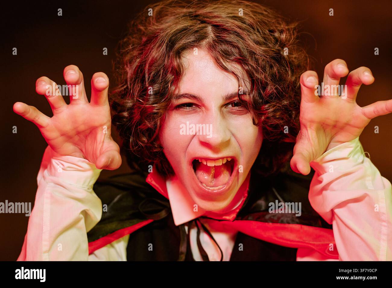 Portrait d'un adolescent en costume de vampire gesticulant et hurlant à Halloween Banque D'Images