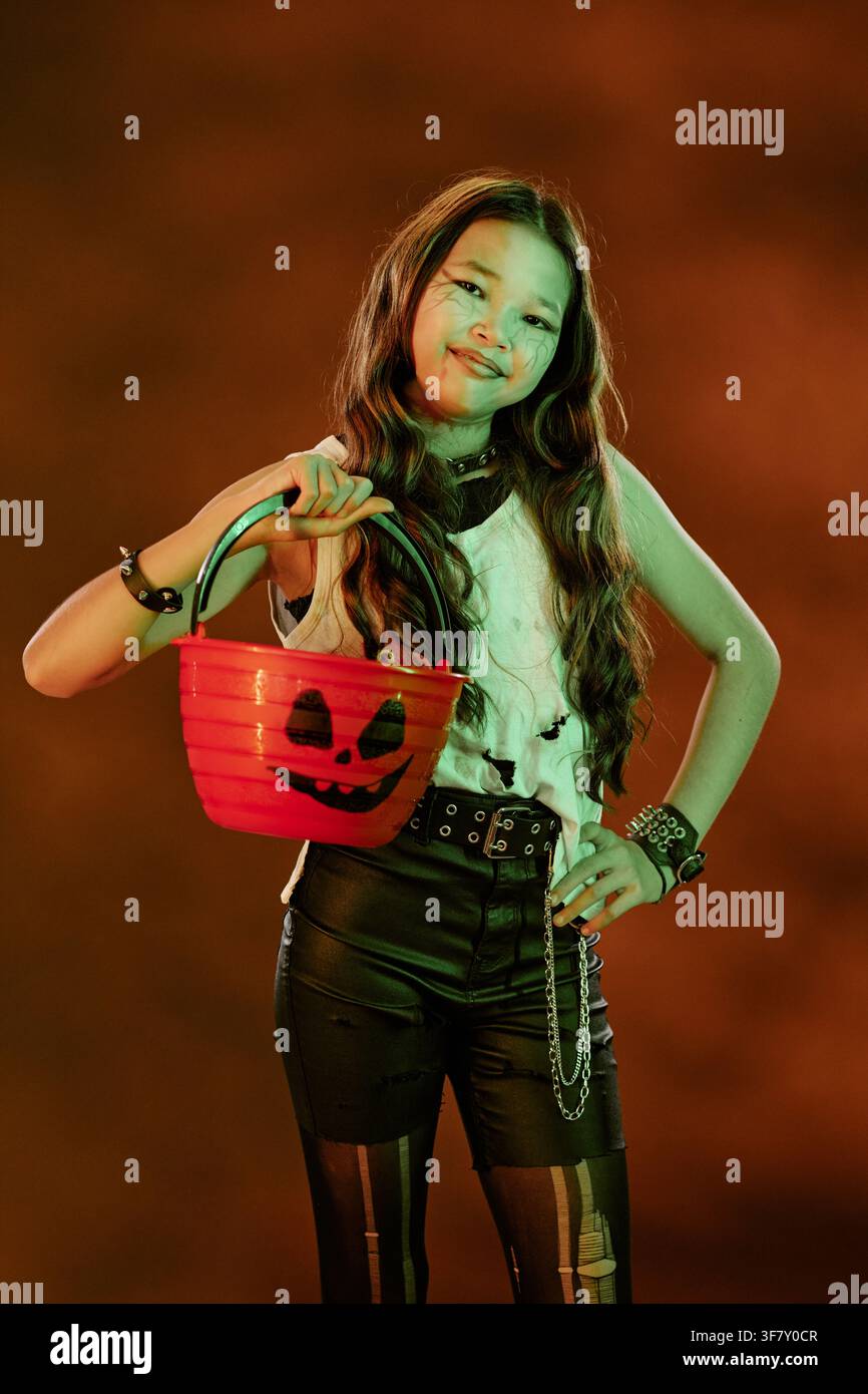 Portrait d'une fille asiatique tenant un pot de citrouille d'Halloween Banque D'Images