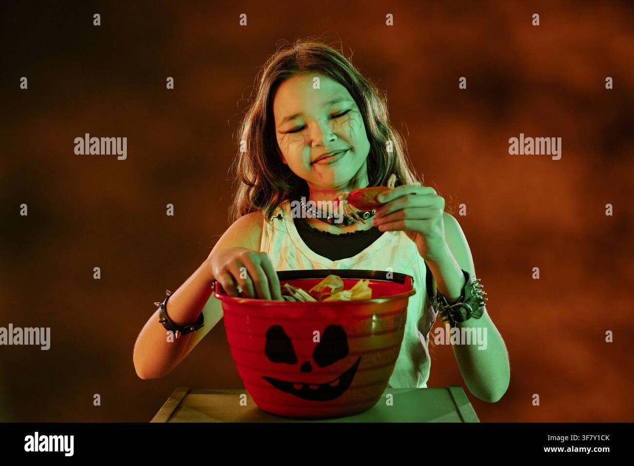 Jeune Asiatique en costume d'Halloween tenant un seau à bonbons Banque D'Images