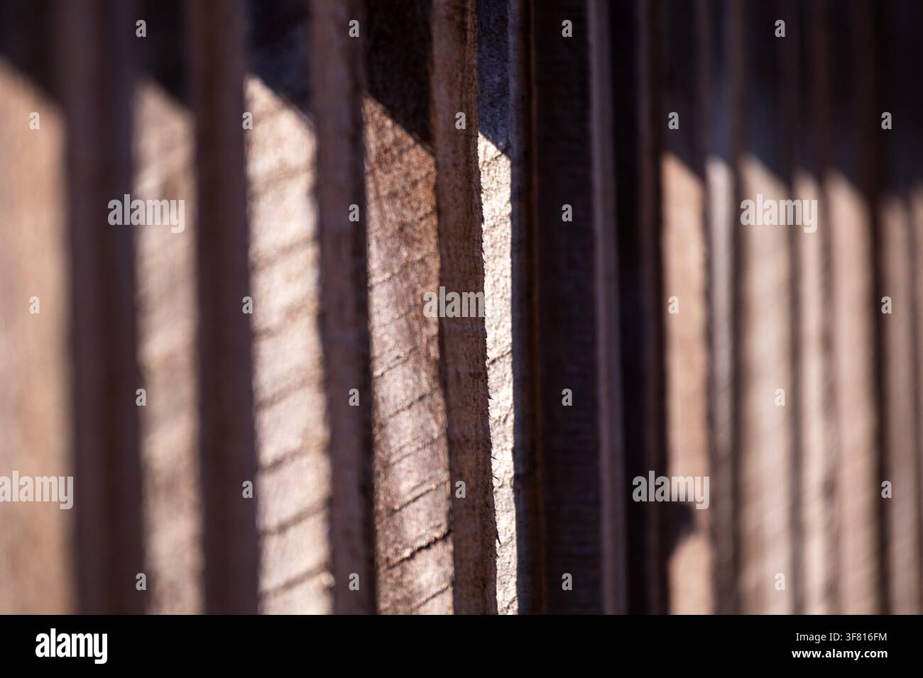 Un cliché en angle d'une clôture en bois rustique montrant les détails alors que la lumière du soleil la frappe, projetant une ombre Banque D'Images