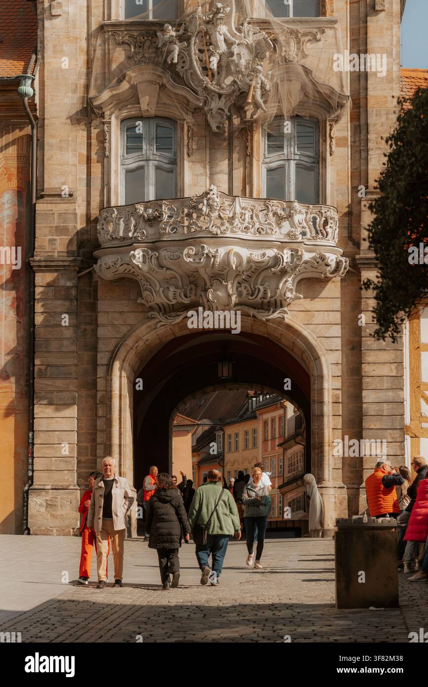 Les visiteurs passent sous la porte baroque ornée de l'Altes Rathaus de Bamberg, Bamberg, Bavière, Allemagne, le 7 mars 2026. Banque D'Images