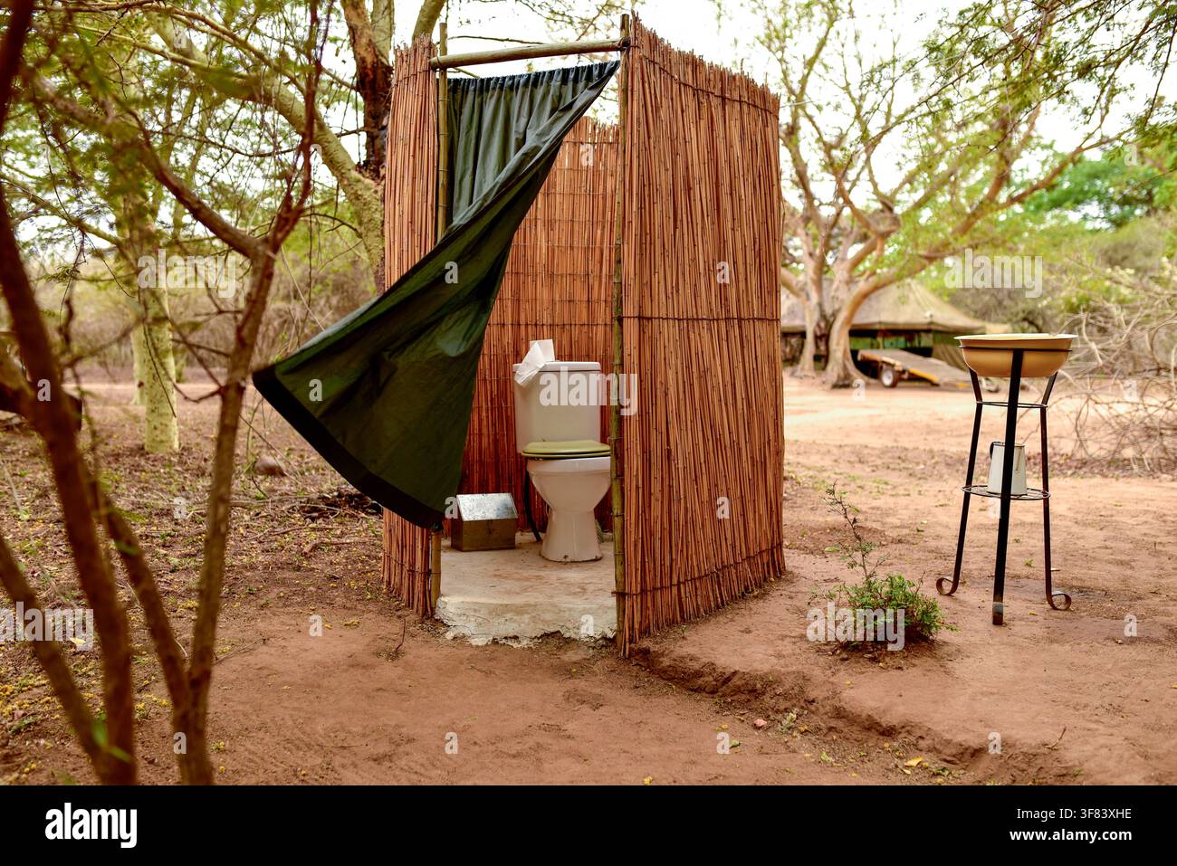 Toilette extérieure en buisson avec paravent en roseaux et abri en toile dans un camp safari Banque D'Images