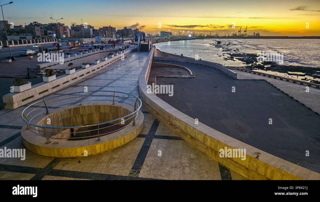 Vue du coucher de soleil sur le front de mer à Benghazi montrant la côte et la ligne d'horizon de la ville en Libye Banque D'Images