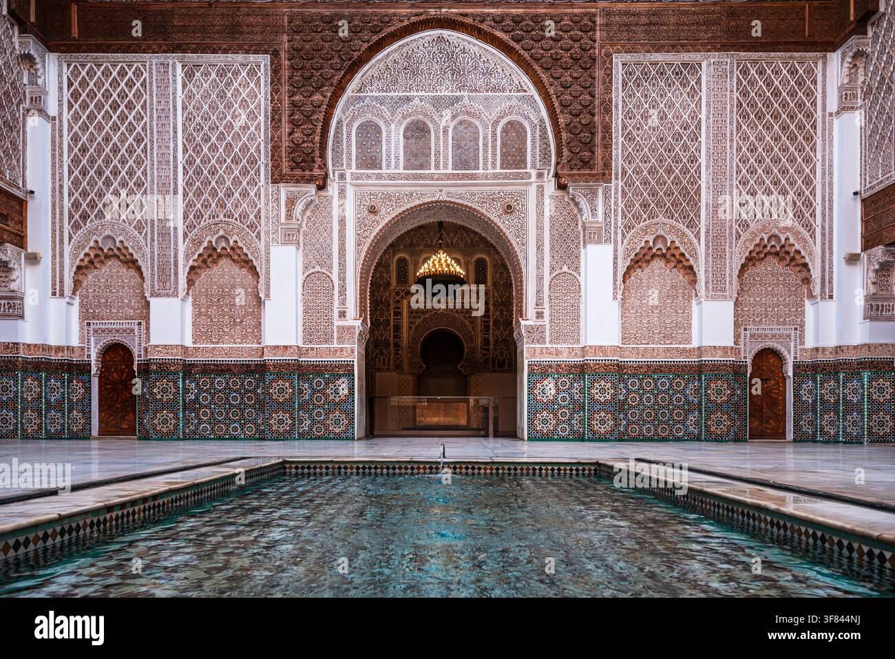 Bassins réfléchissants entourés d'arches et de sculptures dans la cour de la Madrasa Ben Youssef à Marrakesh, Maroc Banque D'Images