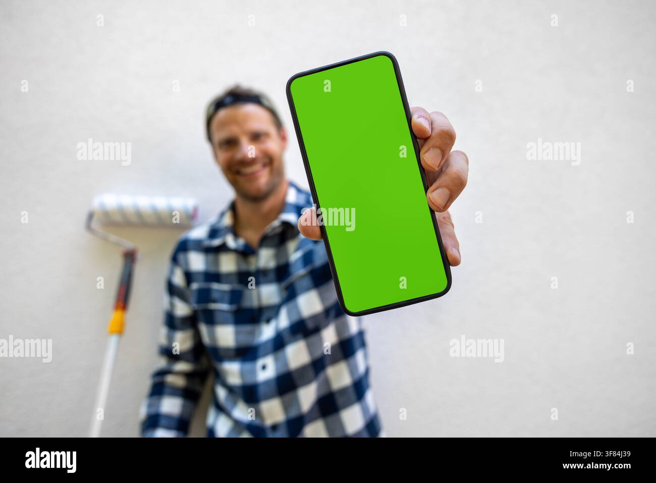 Service de réservation en ligne pour un artisan. Homme montrant un smartphone avec écran vert. Services de réparation domestique Banque D'Images