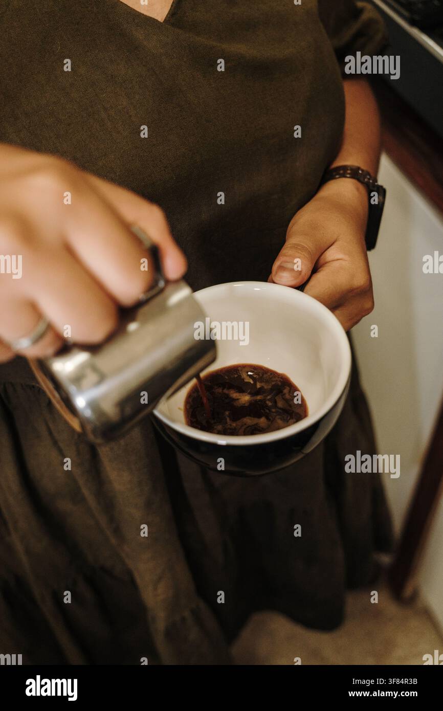 Un espresso frais est versé dans une tasse en céramique avant d'ajouter du lait fumé. Préparation d'une boisson café spécialisée artisanale. Banque D'Images