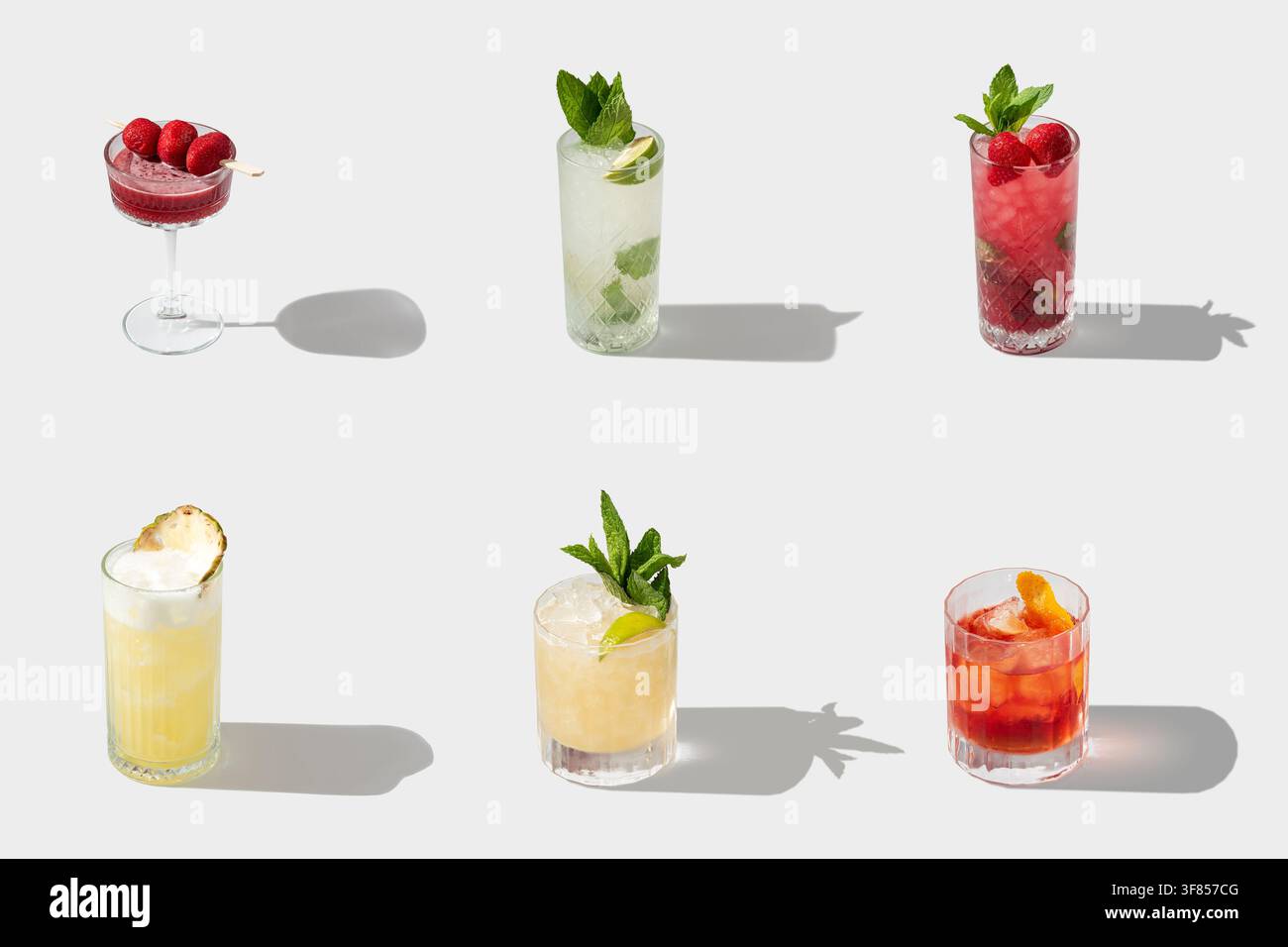 Collection de cocktails d'été colorés avec garnitures de fruits et ombres allongées sur fond blanc Banque D'Images