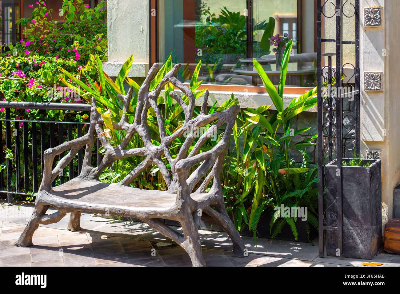 Un banc en pierre décoratif rappelant des branches d'arbre se trouve sur une terrasse extérieure près des plantes. Œuvre d'art de mobilier de jardin créatif, conception extérieure de resort Banque D'Images