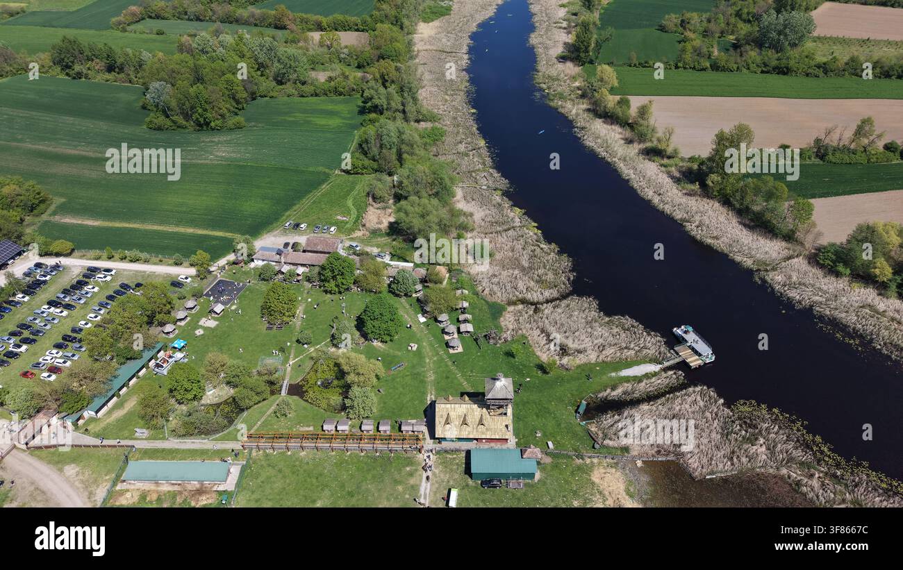 Vue aérienne de la réserve naturelle spéciale de Zasavica présentant la rivière sinueuse, les zones humides luxuriantes, les installations pour les visiteurs et un parking à Zasavic Banque D'Images