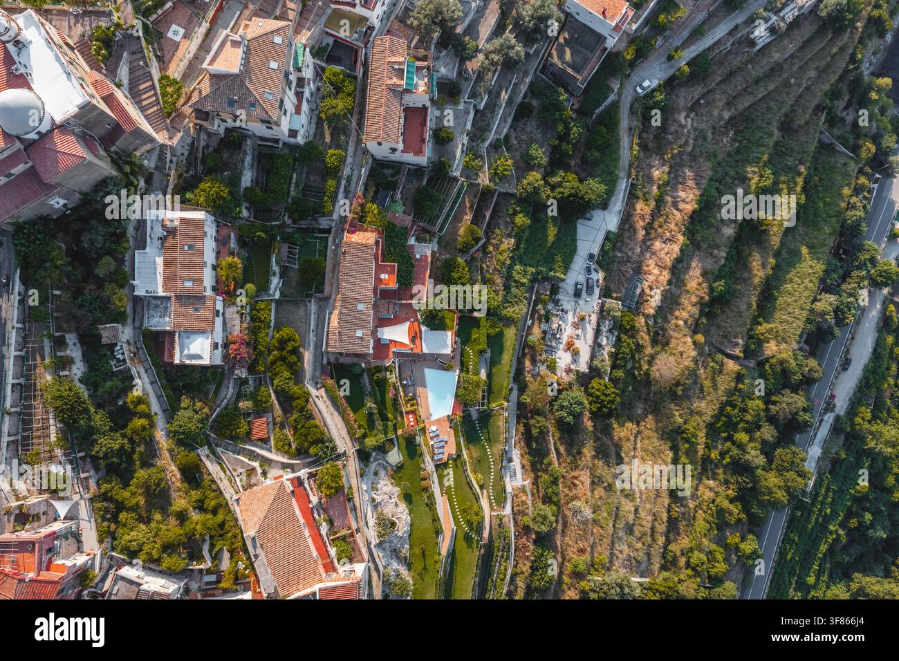 Vue aérienne du village en colline aux toits en terre cuite, aux jardins en terrasses et aux routes sinueuses surplombant le paysage méditerranéen à Raito, Am Banque D'Images
