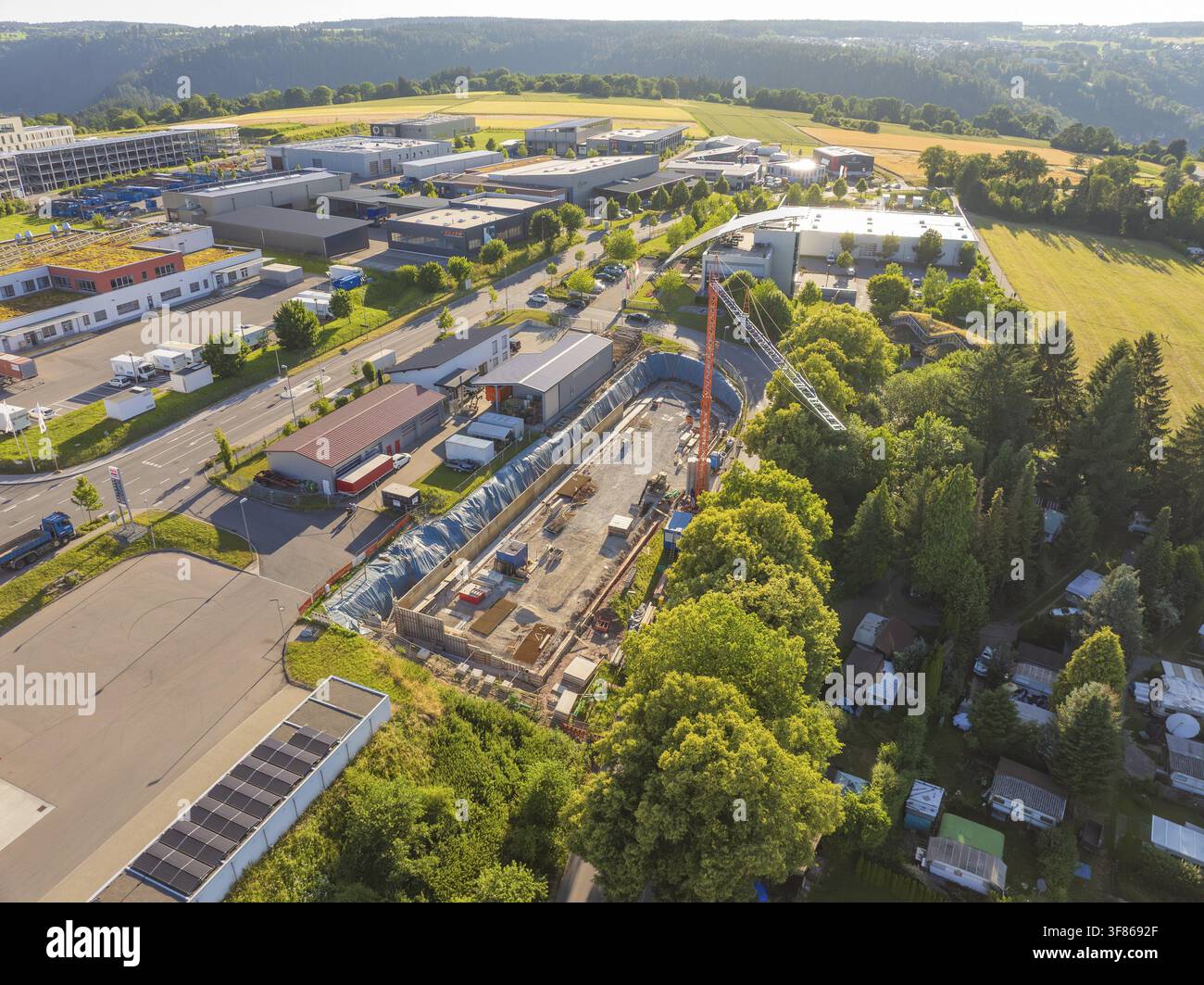Vue aérienne d'un site industriel avec des activités de construction majeures, adjacent à des champs et des rangées d'arbres, Parkhaus Bau, Calw, Allemagne Banque D'Images