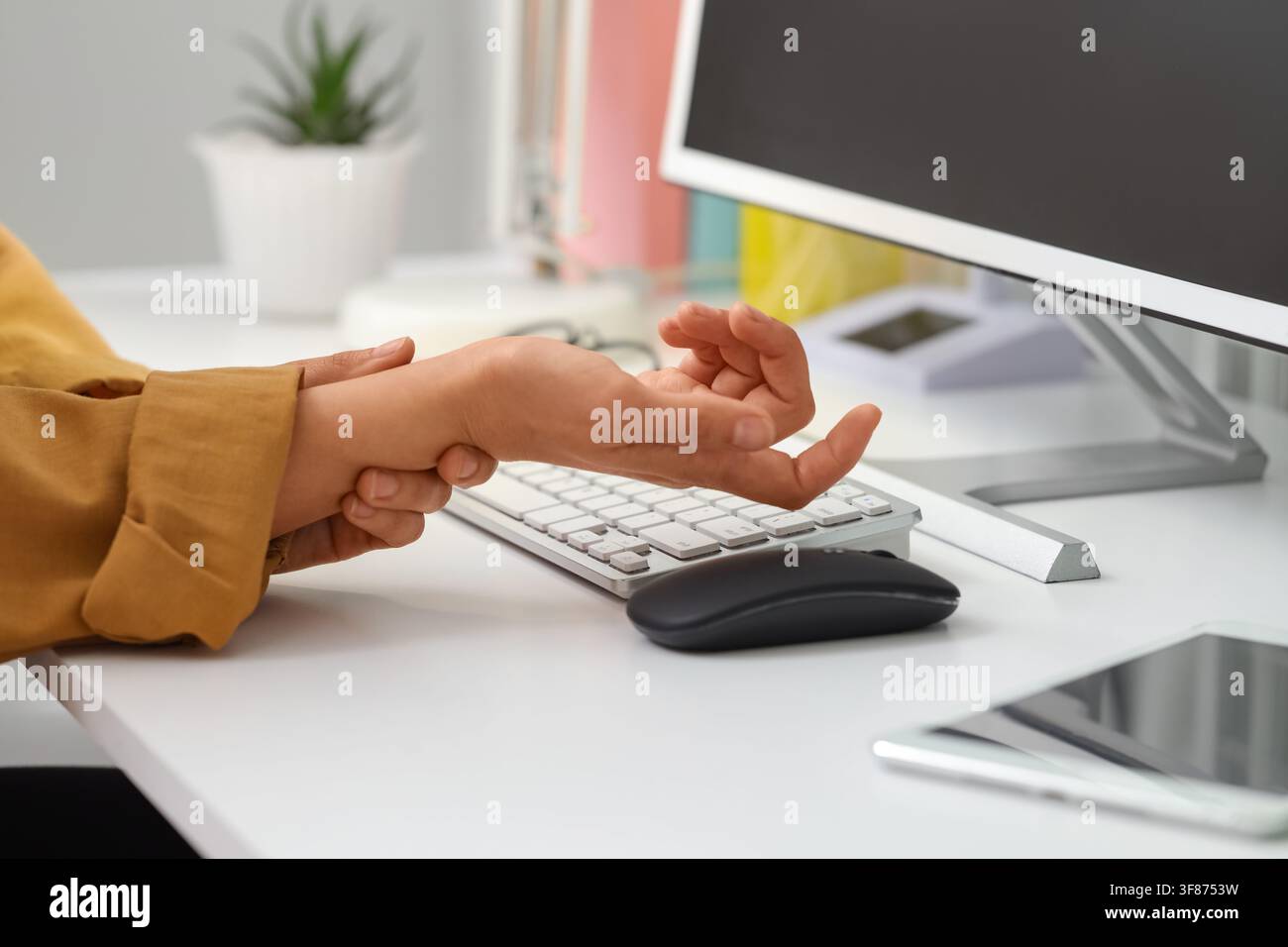 Femme souffrant de douleurs au poignet à table dans le bureau Banque D'Images