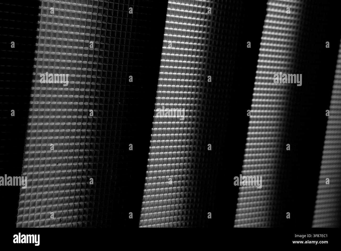 Photo macro d'un motif grille minimaliste avec un éclairage diagonal à contraste élevé. Banque D'Images