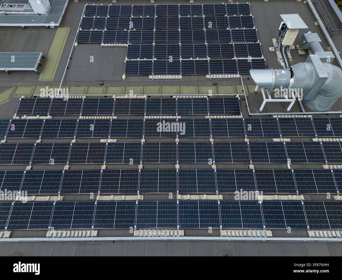 Vue aérienne d'un champ de panneaux solaires montés en rangées sur un toit plat commercial, concept détaillé d'énergie renouvelable et d'installation photovoltaïque. Banque D'Images