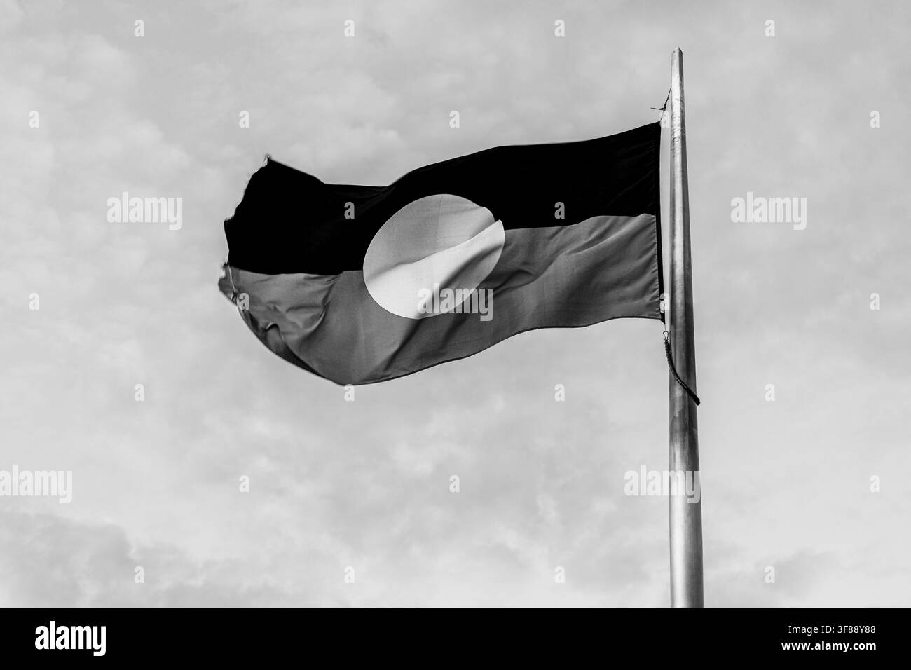 Drapeau rouge, noir et jaune des aborigènes d'Australie flottant au vent à Alice Springs, Territoire du Nord, Australie en noir et blanc Banque D'Images