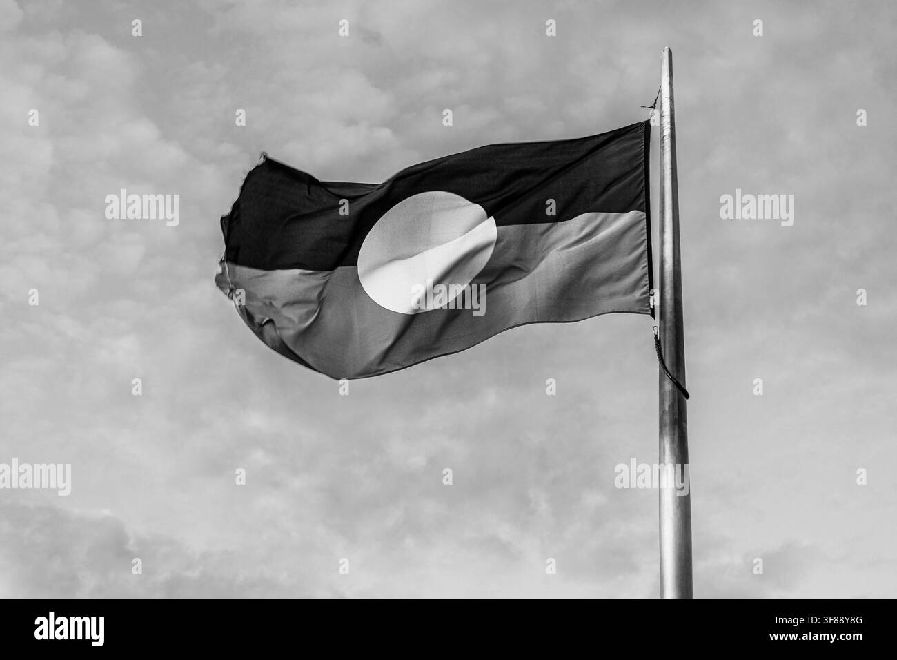 Drapeau rouge, noir et jaune des aborigènes d'Australie flottant au vent à Alice Springs, Territoire du Nord, Australie en noir et blanc Banque D'Images