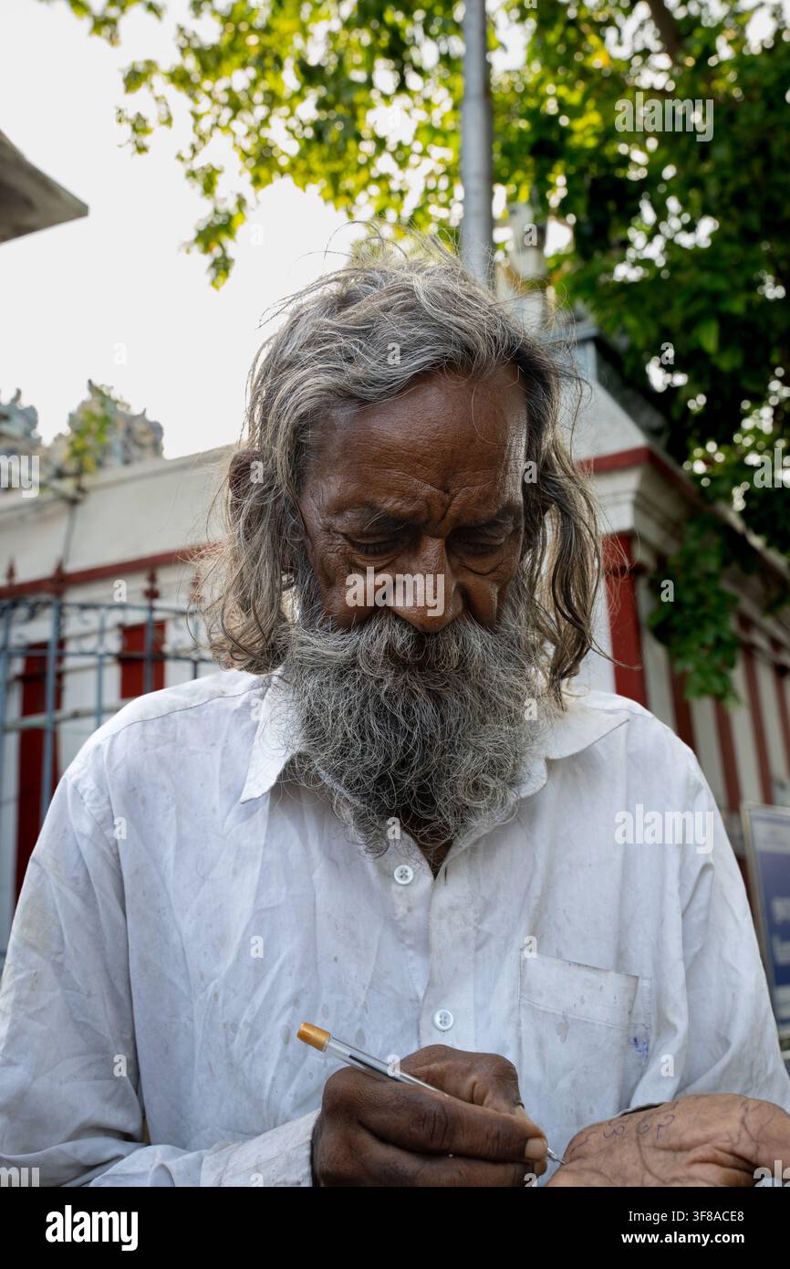 Chennai, Inde – 2 août 2026 : Vieil homme indien à la longue barbe grise regardant vers le bas tout en tenant un stylo Banque D'Images