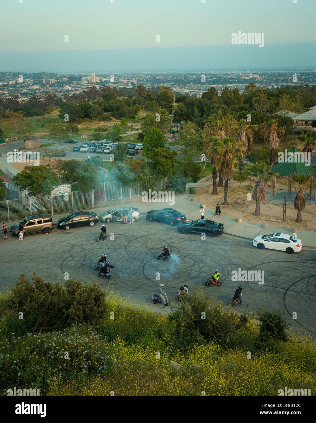 Un groupe de personnes sur des scooters laisse des traces de pneus et de la fumée sur un parking à Elysian Park, Los Angeles, Californie Banque D'Images