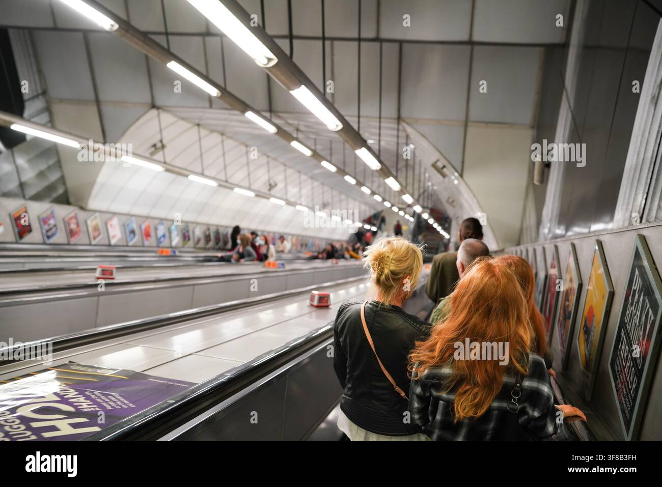 Les navetteurs descendent un escalator emblématique des profondeurs du métro londonien pour accéder aux quais et voyager à travers la ville. Banque D'Images