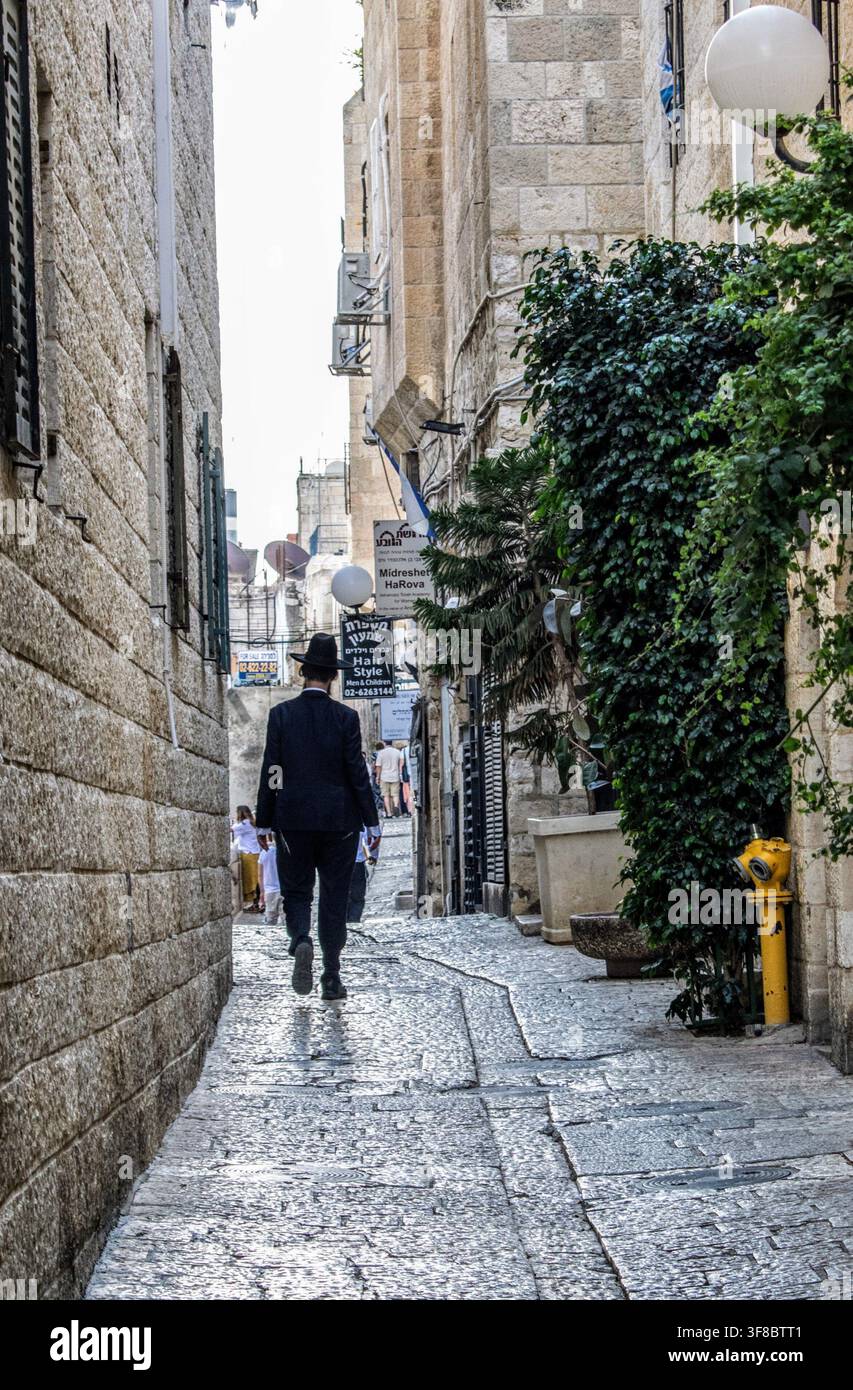 Ruelle étroite de la Vieille Ville de Jérusalem avec un homme en costume noir s'éloignant Banque D'Images