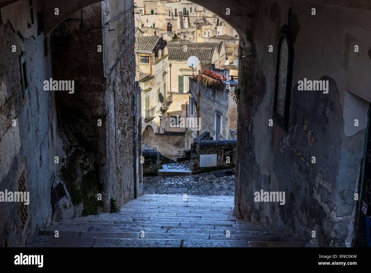 Vue d'un escalier étroit en pierre menant à travers une ruelle ancienne vers les Sassi di Matera historiques, avec des murs en pierre usés et traditionnels Banque D'Images