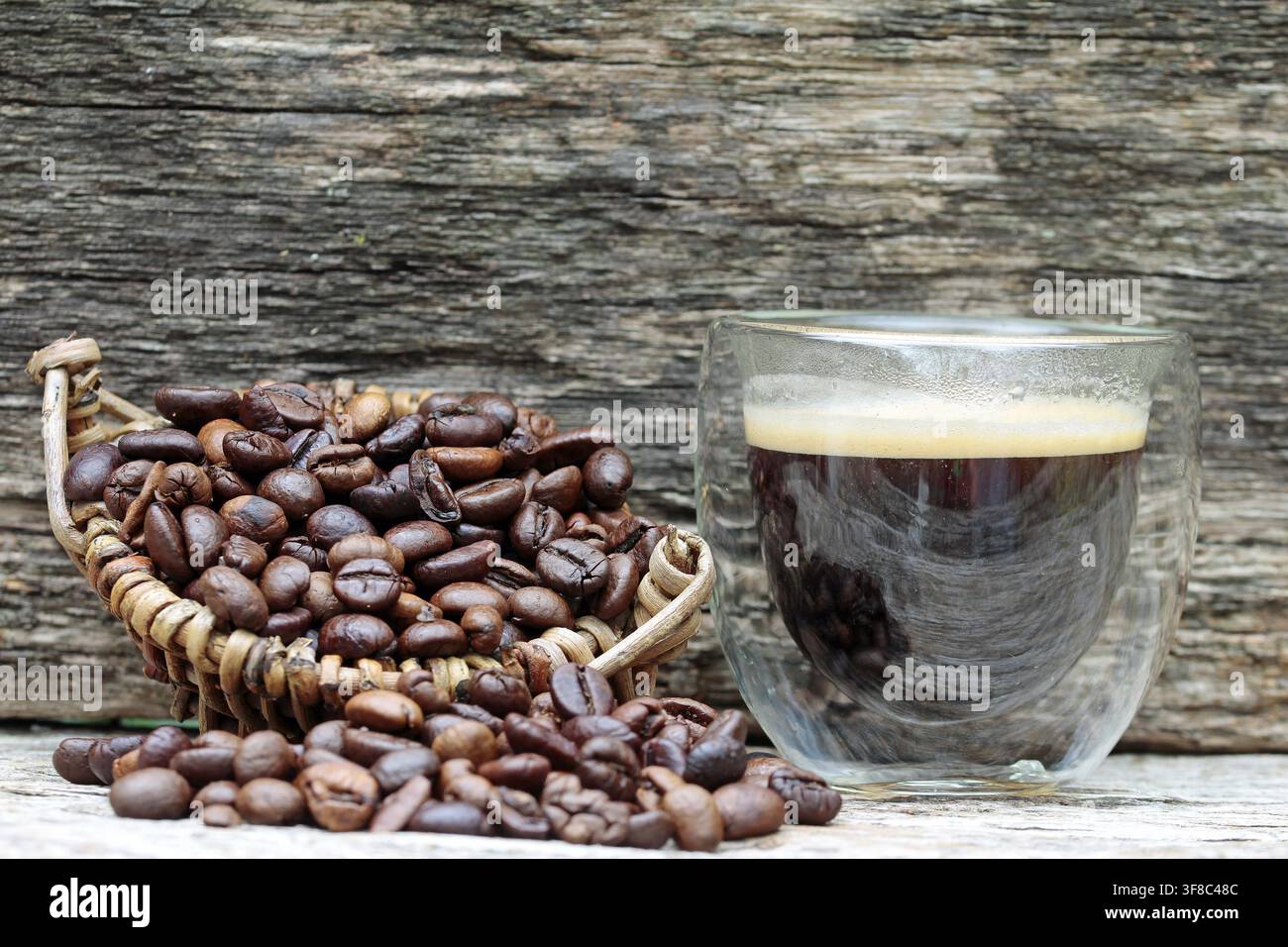 Grains de café dans un panier à côté d'une tasse à espresso en verre sur un fond en bois. Horn-Bad Meinberg Banque D'Images