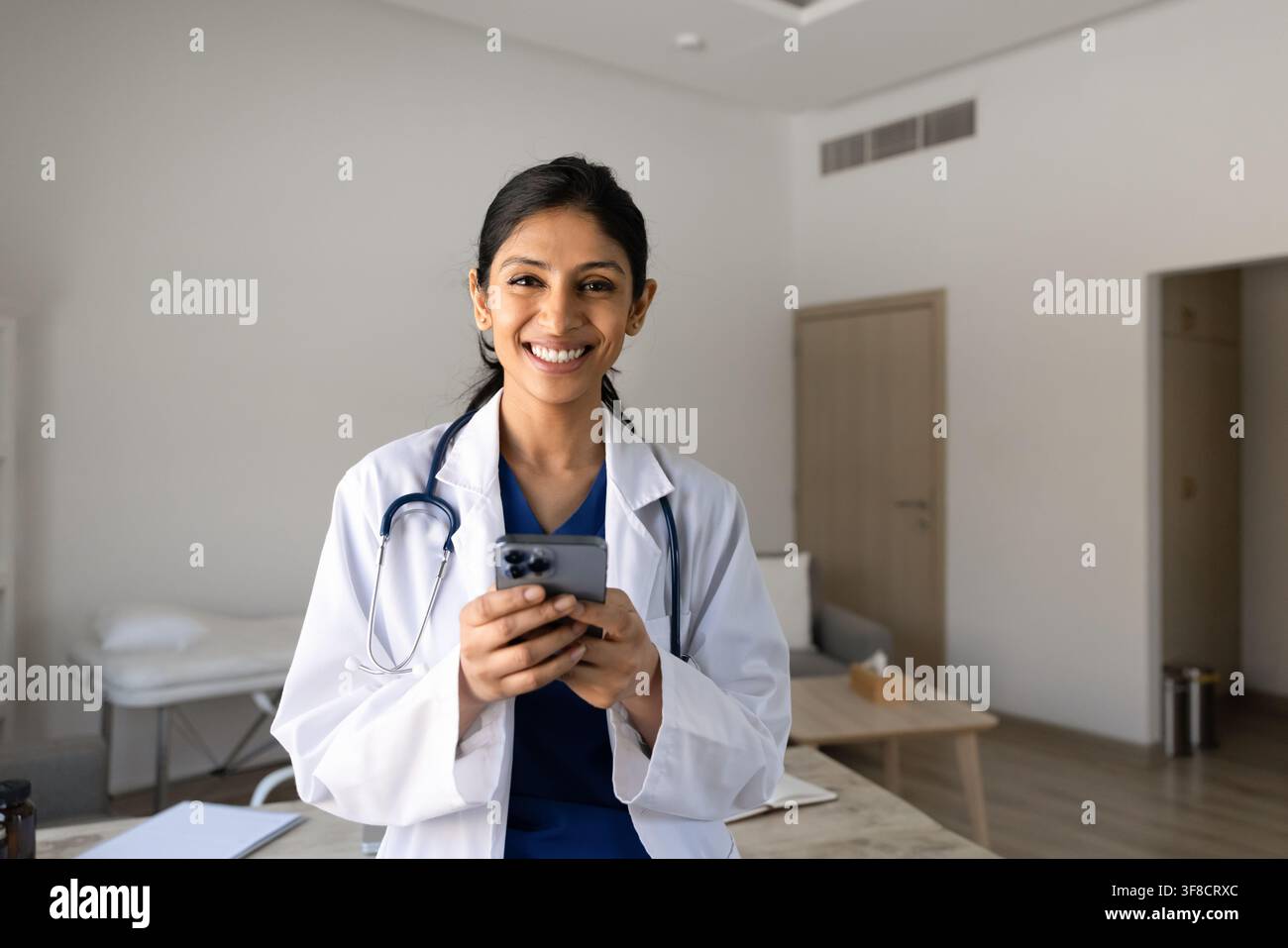 Portrait d'une médecin souriante envoyant un message sur son smartphone Banque D'Images