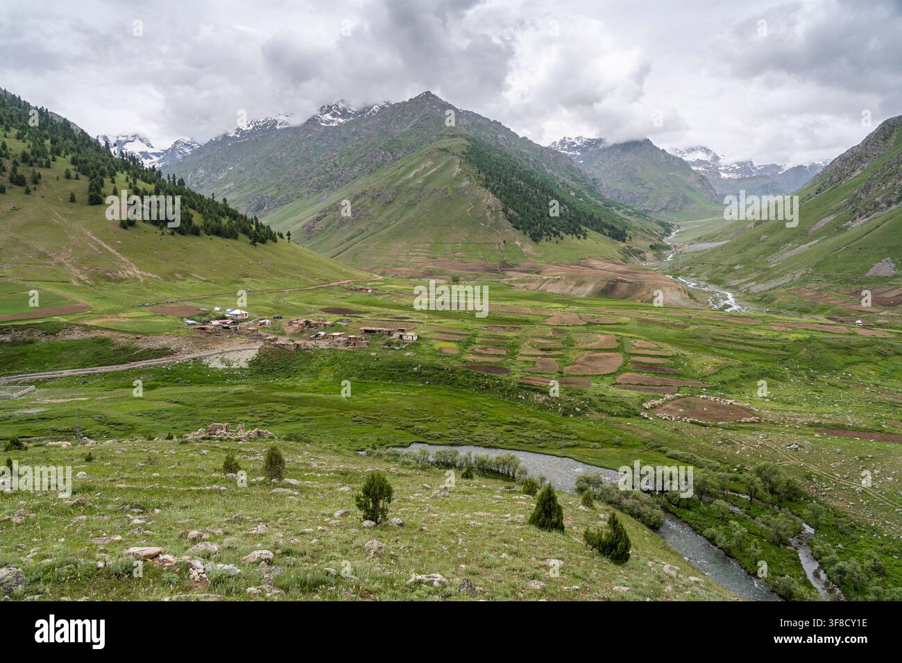 Paysage montagneux rural avec un village sous un ciel orageux dans le parc national de Deosai, Astore, Gilgit Baltistan, Pakistan Banque D'Images