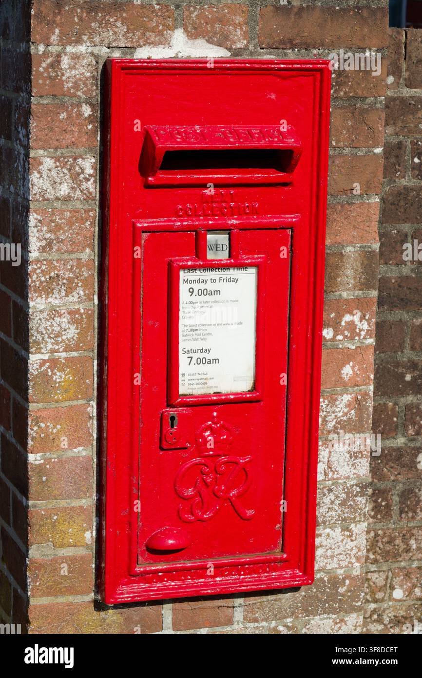 Boîte aux lettres peinte en rouge Royal Mail. George VI, rectangulaire et intégrée dans un mur de briques. Banque D'Images