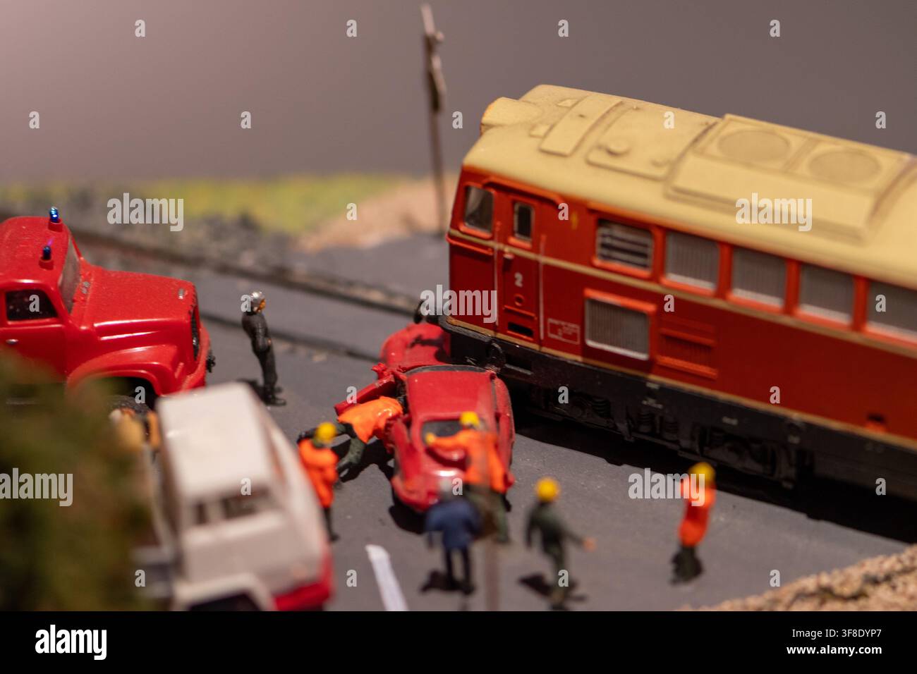 Une photographie en gros plan montre un diorama miniature d'accident ferroviaire avec une locomotive rouge, une voiture rouge écrasée, des véhicules d'urgence et de petites figurines sur un Banque D'Images