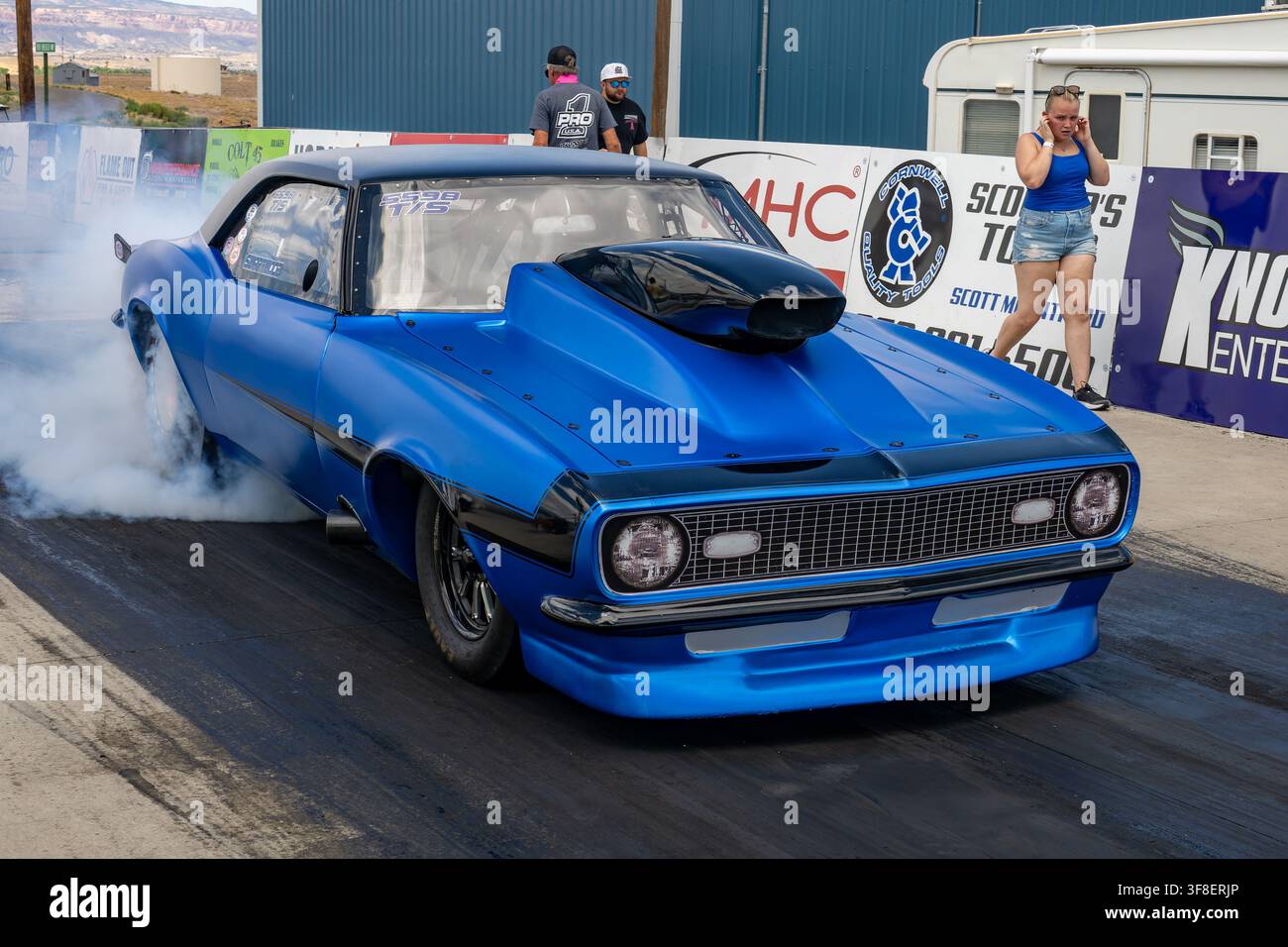 Un pilote de dragster brûle ses pneus avant la course sur le Western Colorado Dragway à Grand Junction, Colorado. Brûler les pneus nettoie les débris des surfaces des pneus et Banque D'Images