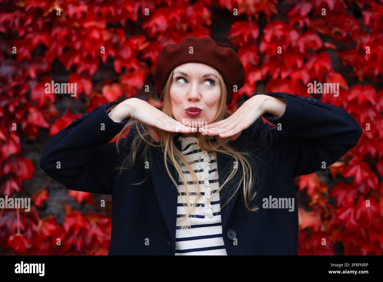 Portrait féminin avec un feuillage rouge vif, une ambiance joyeuse et des vibes de saison d'automne. Banque D'Images