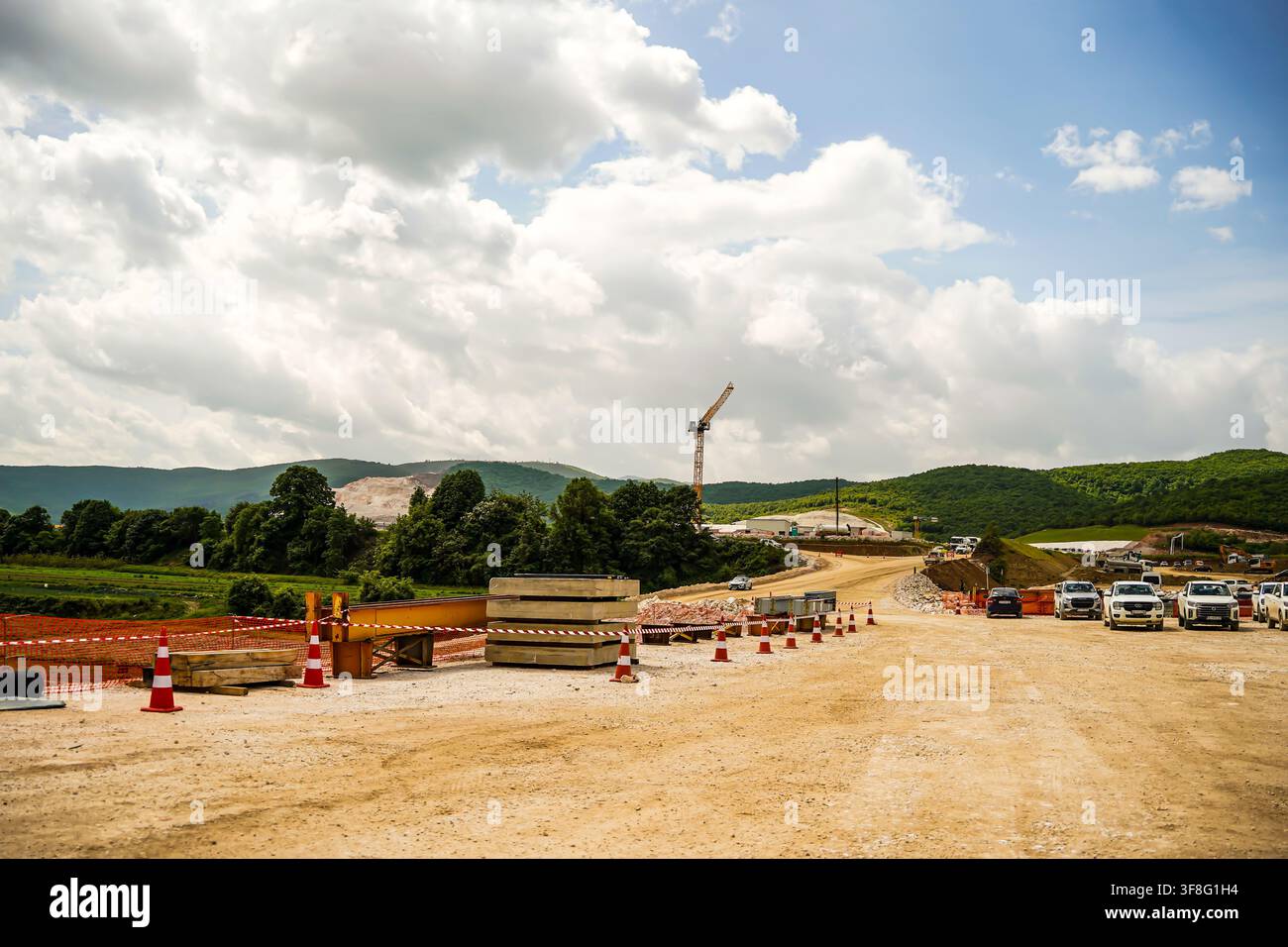 Grand chantier de construction d'autoroute avec grue, véhicules de construction et paysage montagneux Banque D'Images