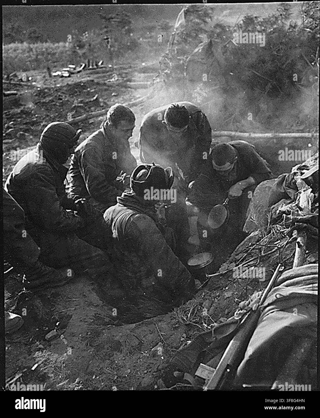 Soldats de la compagnie de mortier lourd, 7e régiment d'infanterie, cuisinant du riz dans une tranchée dans la zone de Kagae-dong, Corée, pendant la guerre de Corée, le 7 décembre 1950. Banque D'Images