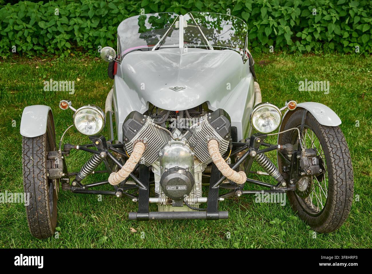 Vue avant d'une voiture de sport triroue grise Triking alimentée par un moteur moto Guzzi V-twin exposé, garée sur une pelouse, Royaume-Uni. Banque D'Images
