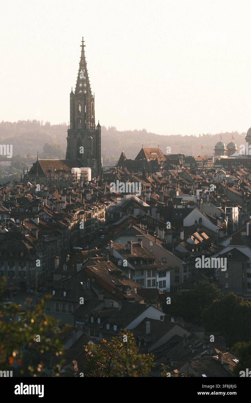 BERNE, SUISSE – 12 AOÛT 2026 : Une lumière chaude du soir tombe sur les toits de la vieille ville de Berne avec la cathédrale du Münster de Berne dominant l'his Banque D'Images