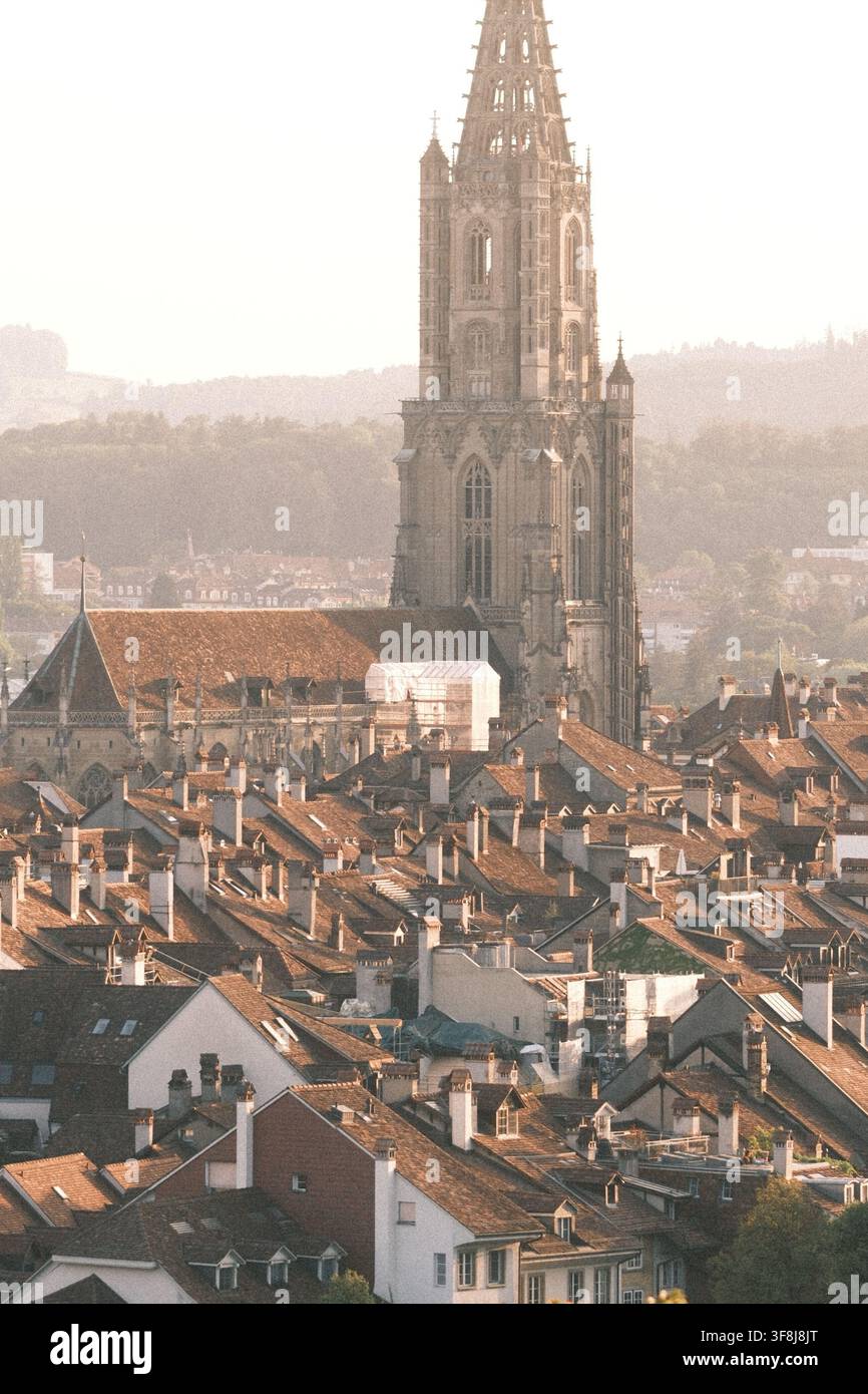 BERNE, SUISSE – 12 AOÛT 2026 : Une lumière chaude du soir tombe sur les toits de la vieille ville de Berne avec la cathédrale du Münster de Berne dominant l'his Banque D'Images