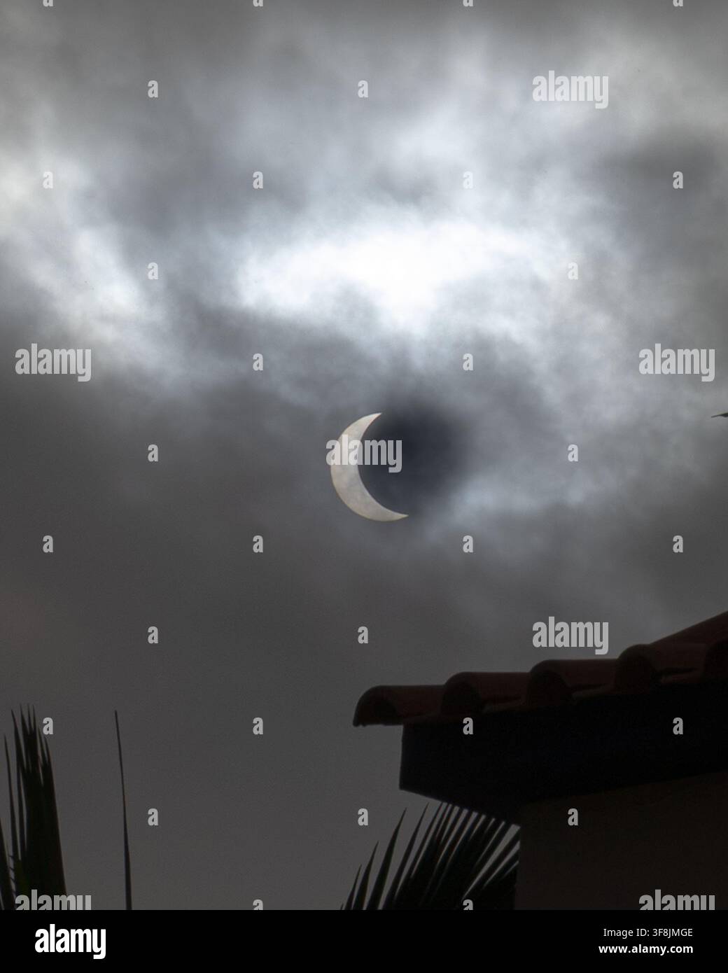 Vue rapprochée du soleil en forme de croissant partiellement recouvert par la lune et visible à travers un ciel nuageux à Madère, Portugal, le 12 août 2026. Partiel Banque D'Images