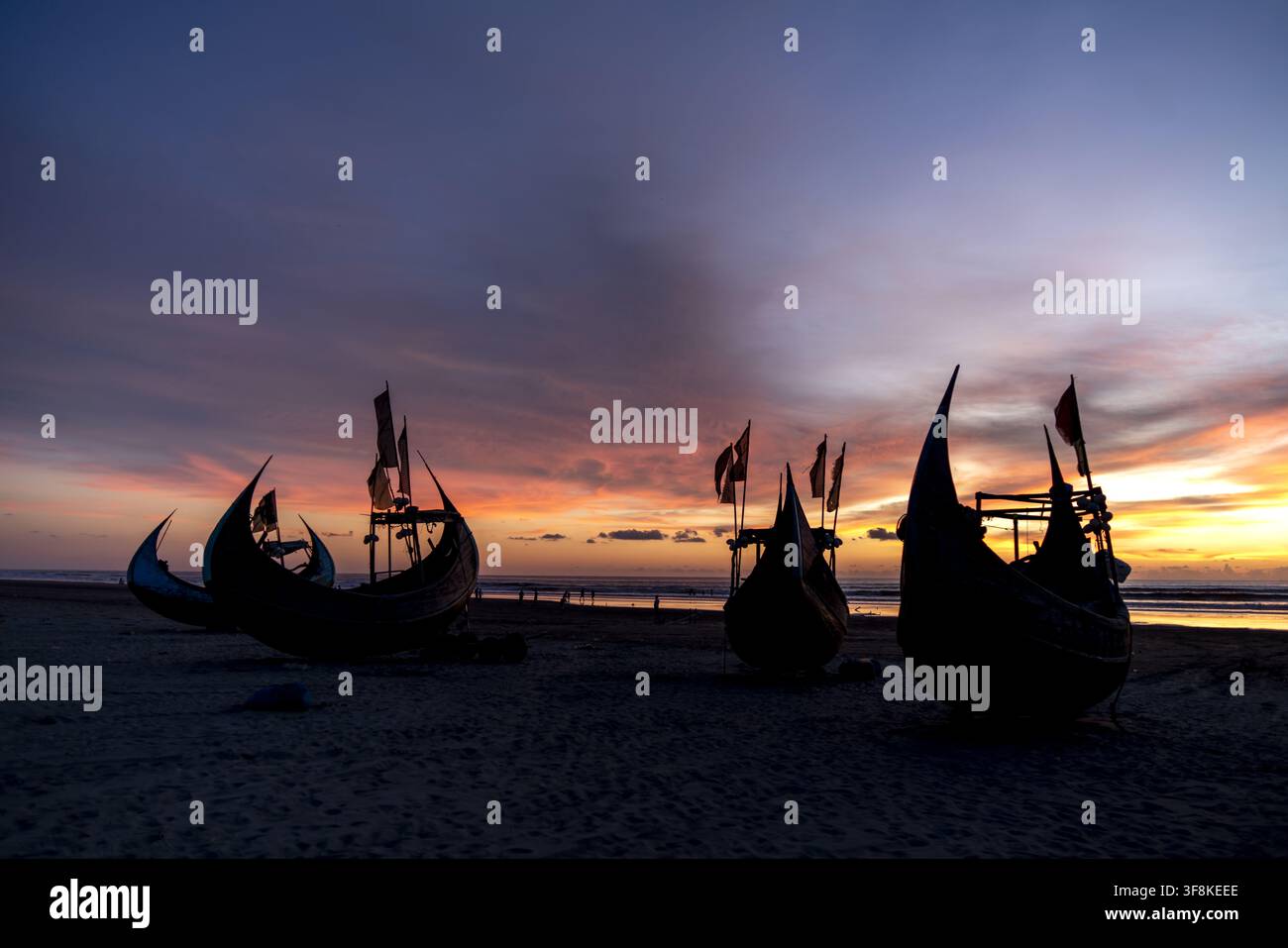 Vue de bateaux de pêche traditionnels en bois silhouettés contre un coucher de soleil vibrant sur la plage d'Inani dans le district de Cox's Bazar, division de Chittagong, Bangladesh. Banque D'Images