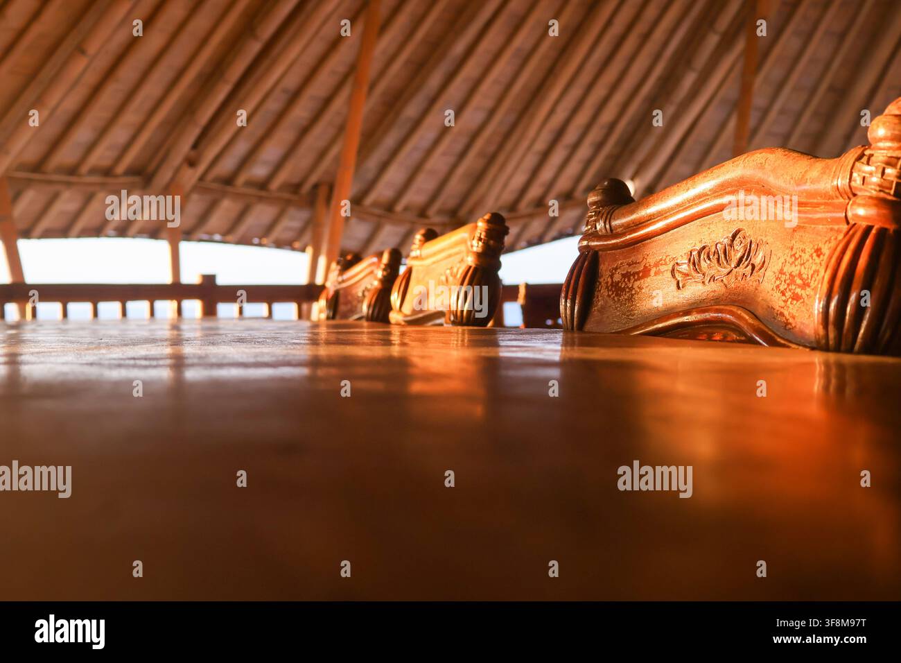 Grossissement d'une chaise en bois sculpté et d'une table dans un pavillon en bambou pendant l'heure dorée au coucher du soleil Banque D'Images